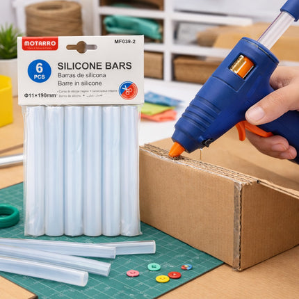 Hot glue gun and silicone bars on a workbench with a package of silicone bars in the background.