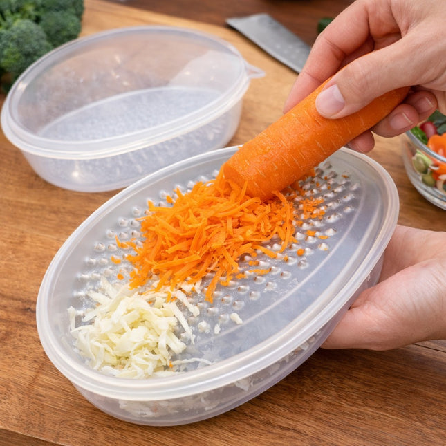 Person using a handheld grater to shred a carrot onto a clear container.