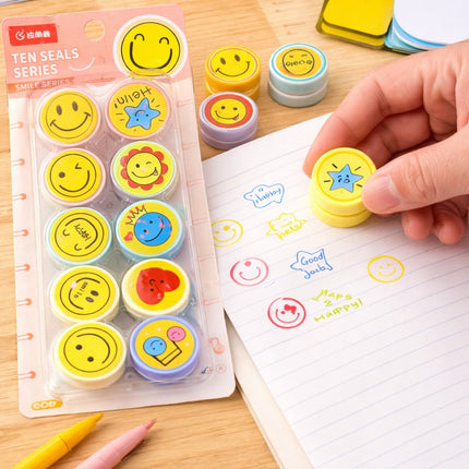 Smiley face stamp set with a hand using one of the stamps on a notebook.