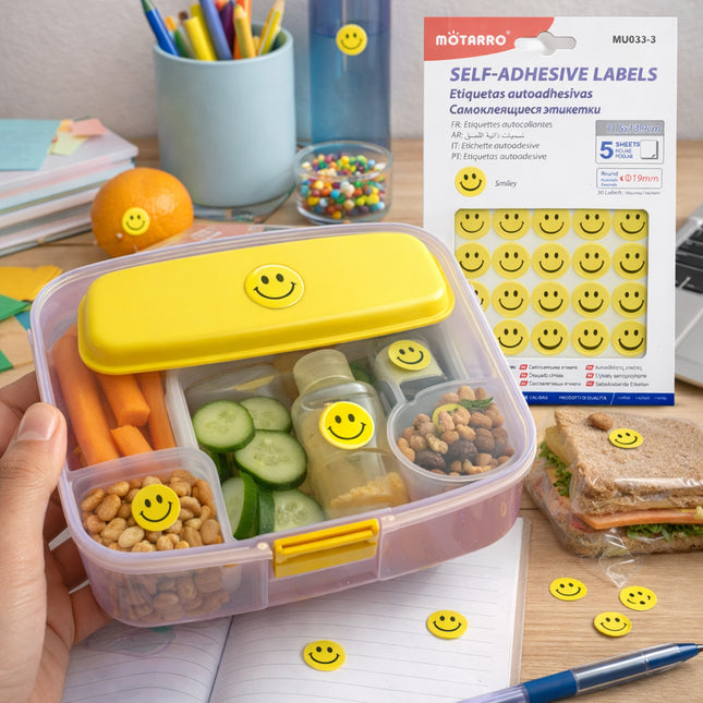 Bento box with smiley face labels on a desk with a package of smiley face labels in the background.
