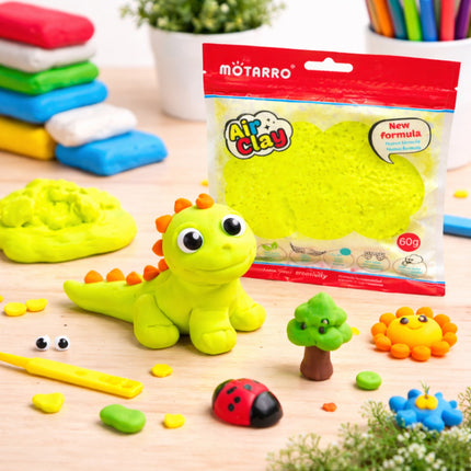 Green dinosaur model made from air clay with packaging and additional clay on a wooden surface.