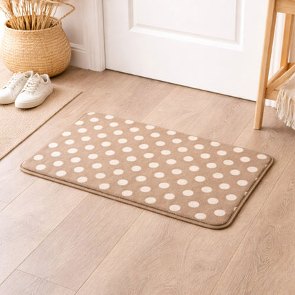 Beige rug with white polka dots on a wooden floor, next to a white door.