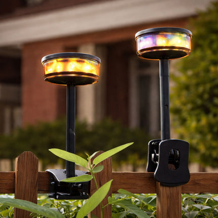 Two solar-powered outdoor lights on a wooden fence with a blurred background.