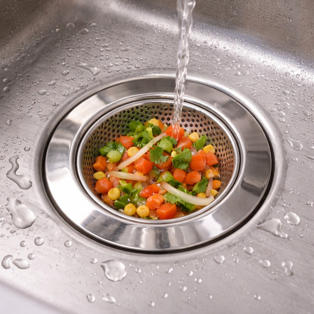 Vegetables being rinsed under running water in a kitchen sink.