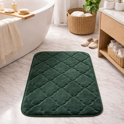 Green bath mat on a bathroom floor with a bathtub, basket, and towel in the background.