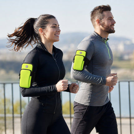 A man and a woman jogging outdoors wearing bright neon yellow armband phone cases on their sleeves.
