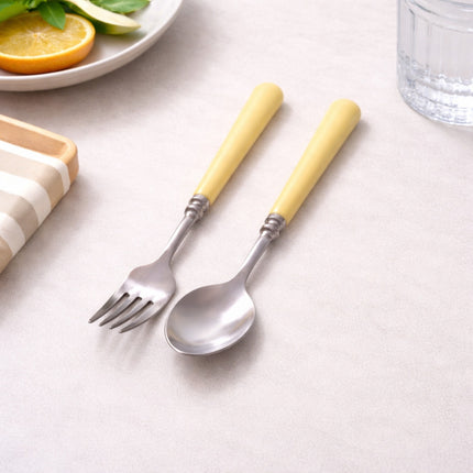 Set of fork and spoon with yellow handles on a light surface