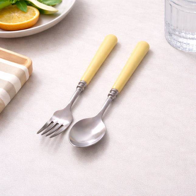 Set of fork and spoon with yellow handles on a light surface