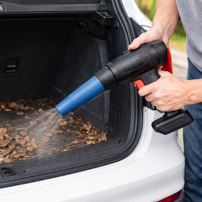 Person using a leaf blower to clean leaves from a car trunk