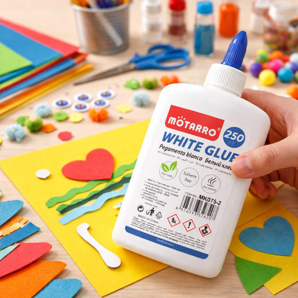 Mоторро white glue bottle held over a craft project with colorful paper hearts and scissors.