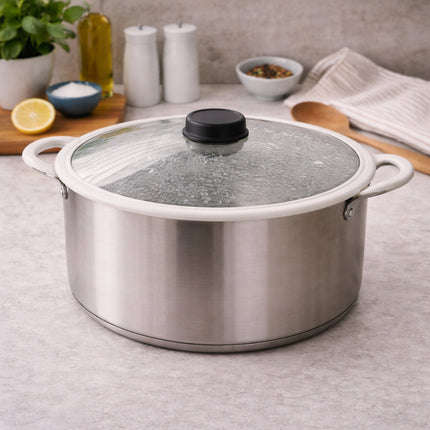 Stainless steel pot with glass lid on a kitchen counter