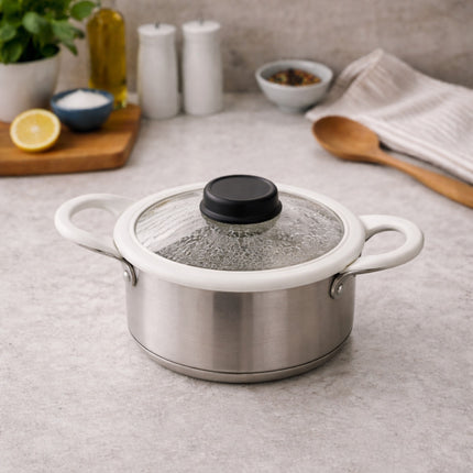 Stainless steel pot with a glass lid on a kitchen counter