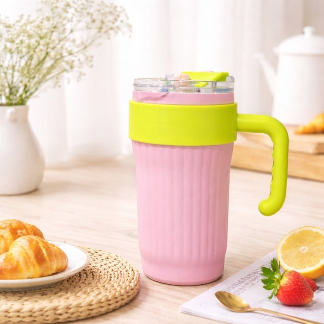 Pink mug with green handle on a table with pastries and lemon