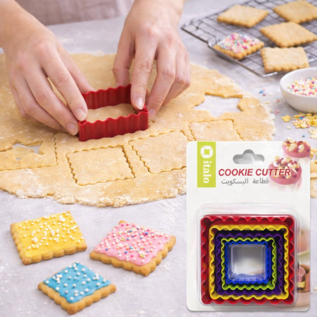 Cookie cutter being used on dough with colorful cookies and packaging in the background
