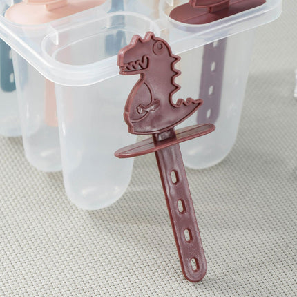 Red dinosaur-shaped popsicle mold on a textured surface with clear plastic molds in the background.
